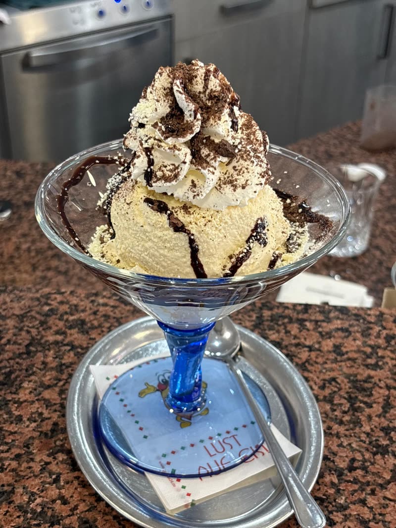 Eisbecher mit Vanilleeis, Sahne, Schokosauce und Schokoraspeln im Glas